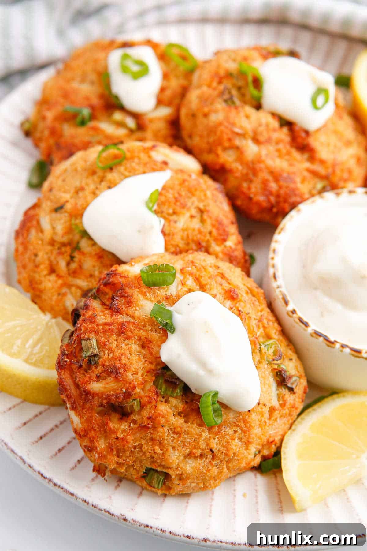 Perfectly Crispy Air-Fried Crab Cakes 8 Air Fryer Crab Cake topped with a generous dollop of tartar sauce and fresh green onions, ready to be enjoyed.