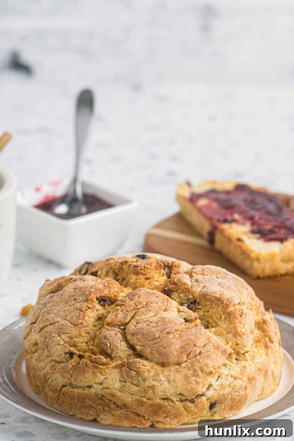 A perfectly baked round loaf of Irish Soda Bread displayed on a simple white plate, ready to be enjoyed.