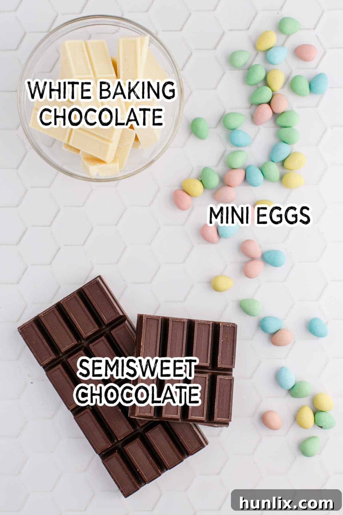 Ingredients for Easter bark laid out on a white patterned surface, including chocolate, white chocolate, and mini eggs, ready for preparation.