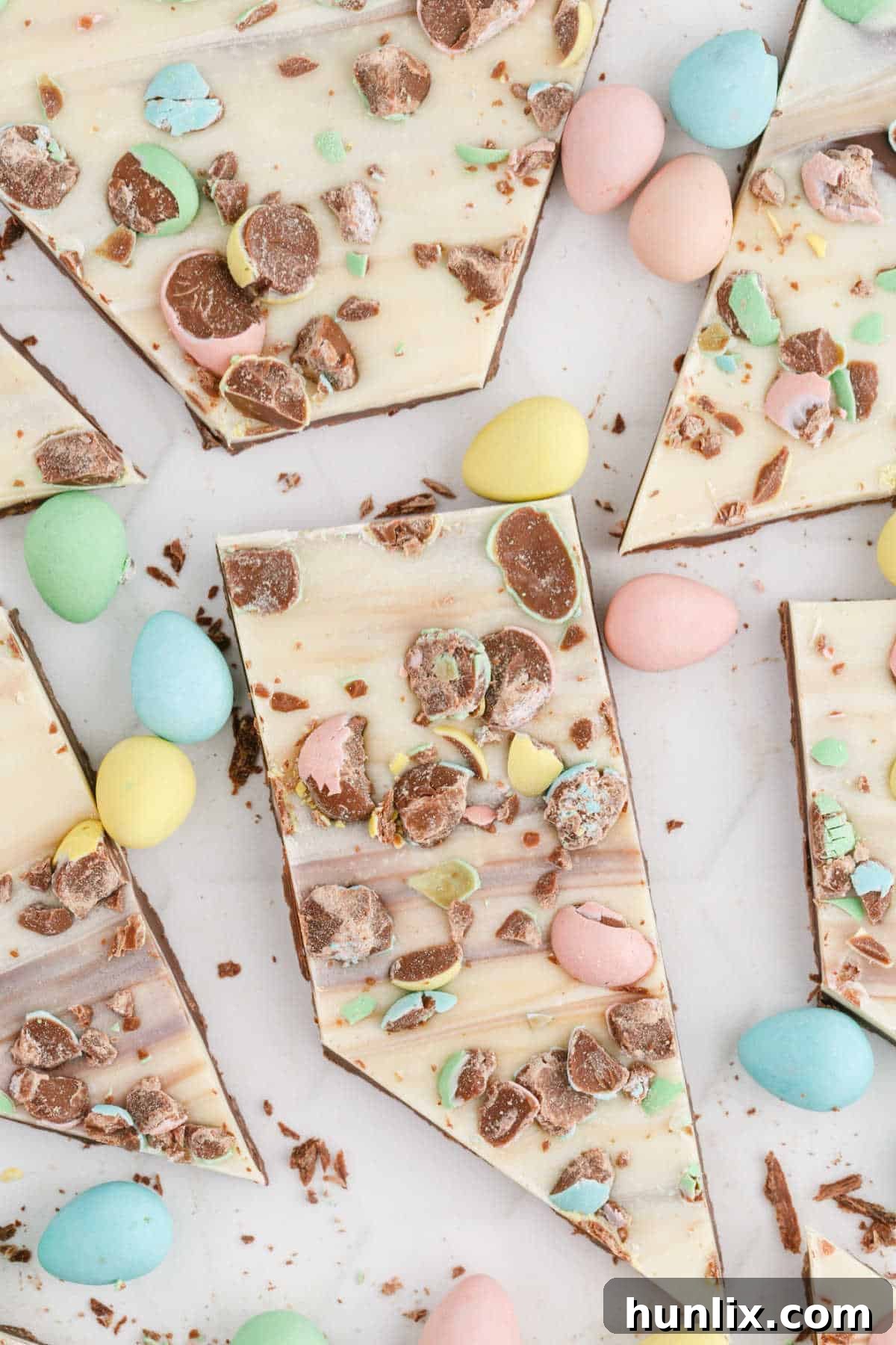 Pieces of finished Easter bark with visible swirls of dark and white chocolate, adorned with colorful mini eggs, arranged for serving.