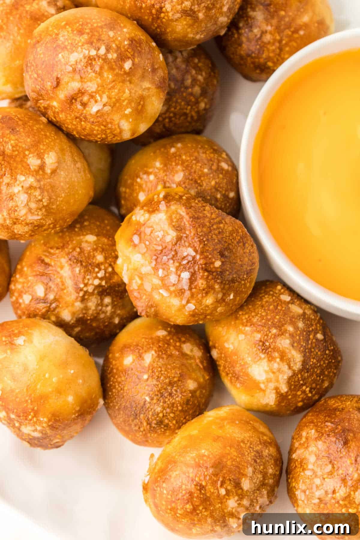 Golden Air Fryer Pretzel Poppers 8 A plate of air fryer pretzel bites with a small bowl of cheese sauce.