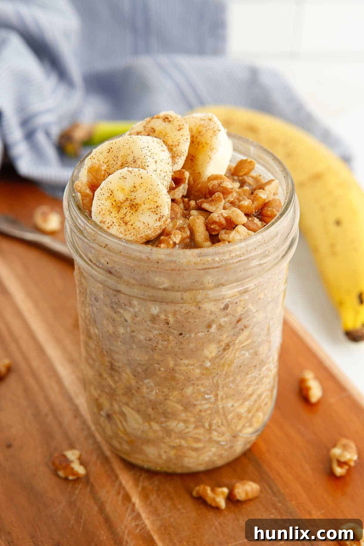 A mason jar filled with Banana Bread Overnight Oats, topped with banana slices and a drizzle of maple syrup.