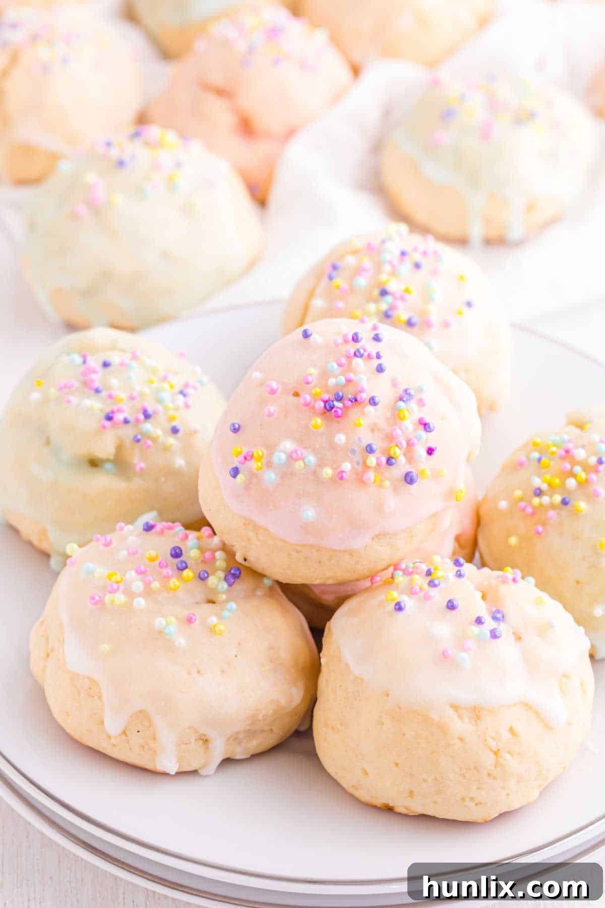 Sweet Italian Easter Delights 11 A close-up of three Italian Easter Cookies with different pastel glazes and sprinkles on a white plate.
