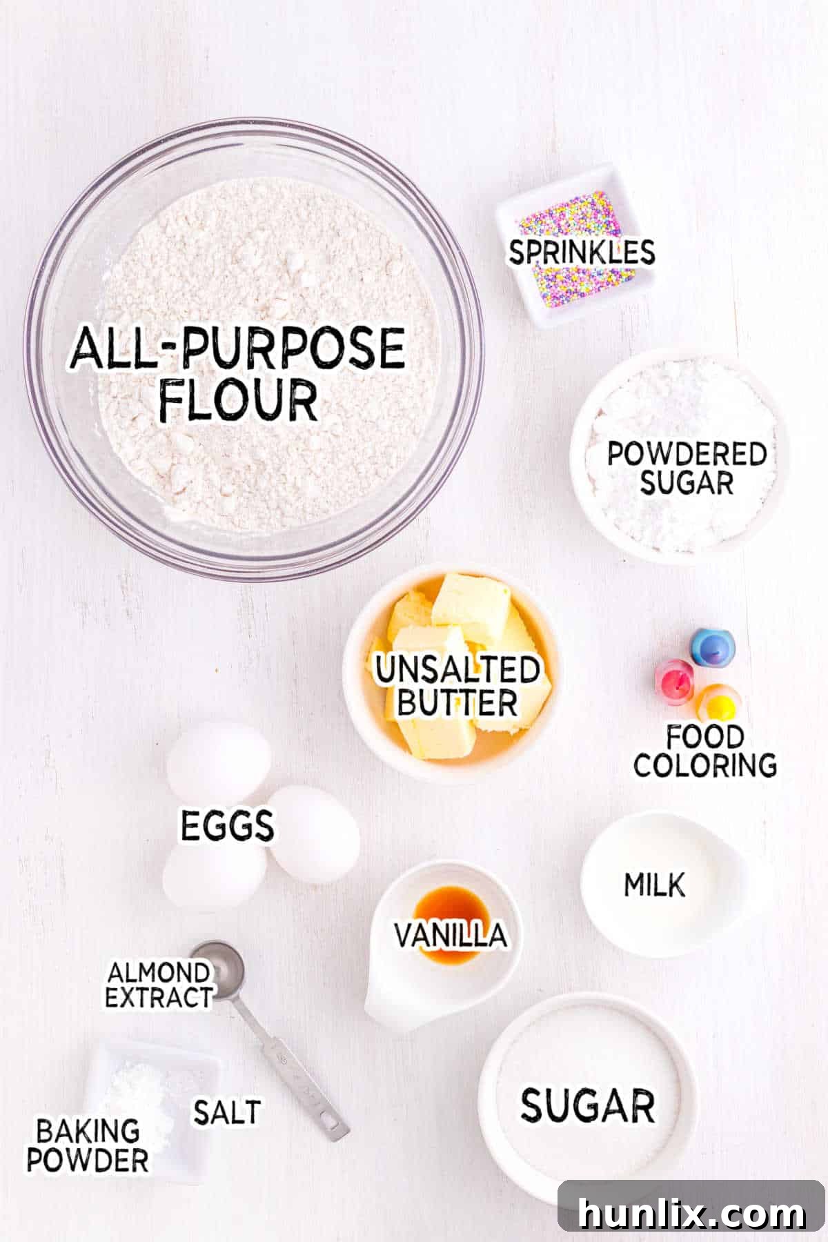 Sweet Italian Easter Delights 3 A flat lay of all the ingredients needed to make Italian Easter Cookies, including flour, sugar, butter, eggs, extracts, powdered sugar, milk, food coloring, and sprinkles.