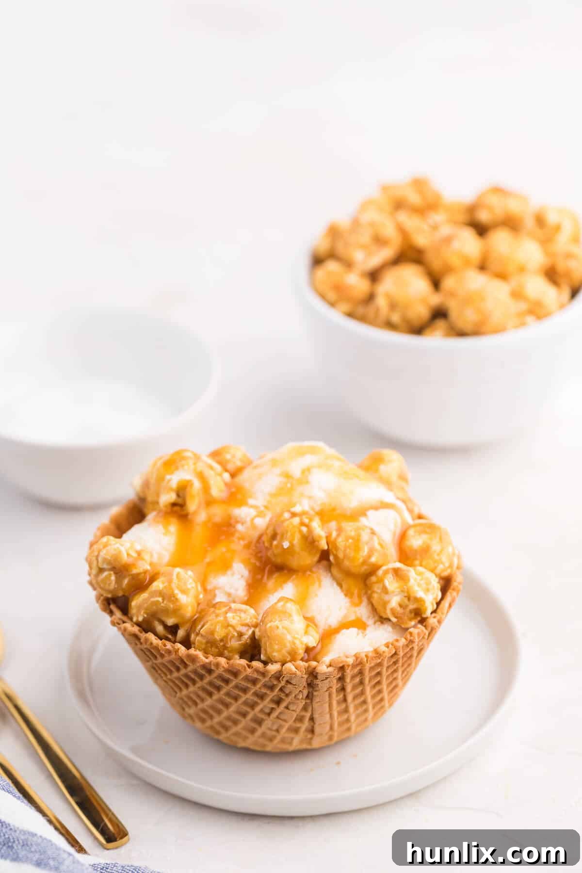 Golden Caramel Crunch Sundae 2 A beautifully presented Caramel Crunch Ice Cream Sundae in a waffle bowl, topped with caramel syrup, sea salt, and caramel popcorn.