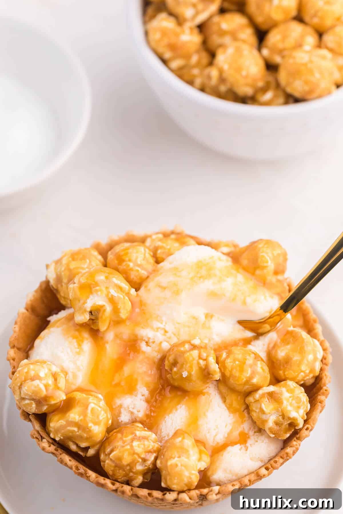 Golden Caramel Crunch Sundae 6 A Caramel crunch ice cream sundae in a waffle bowl with a small golden spoon, inviting you to take a bite.