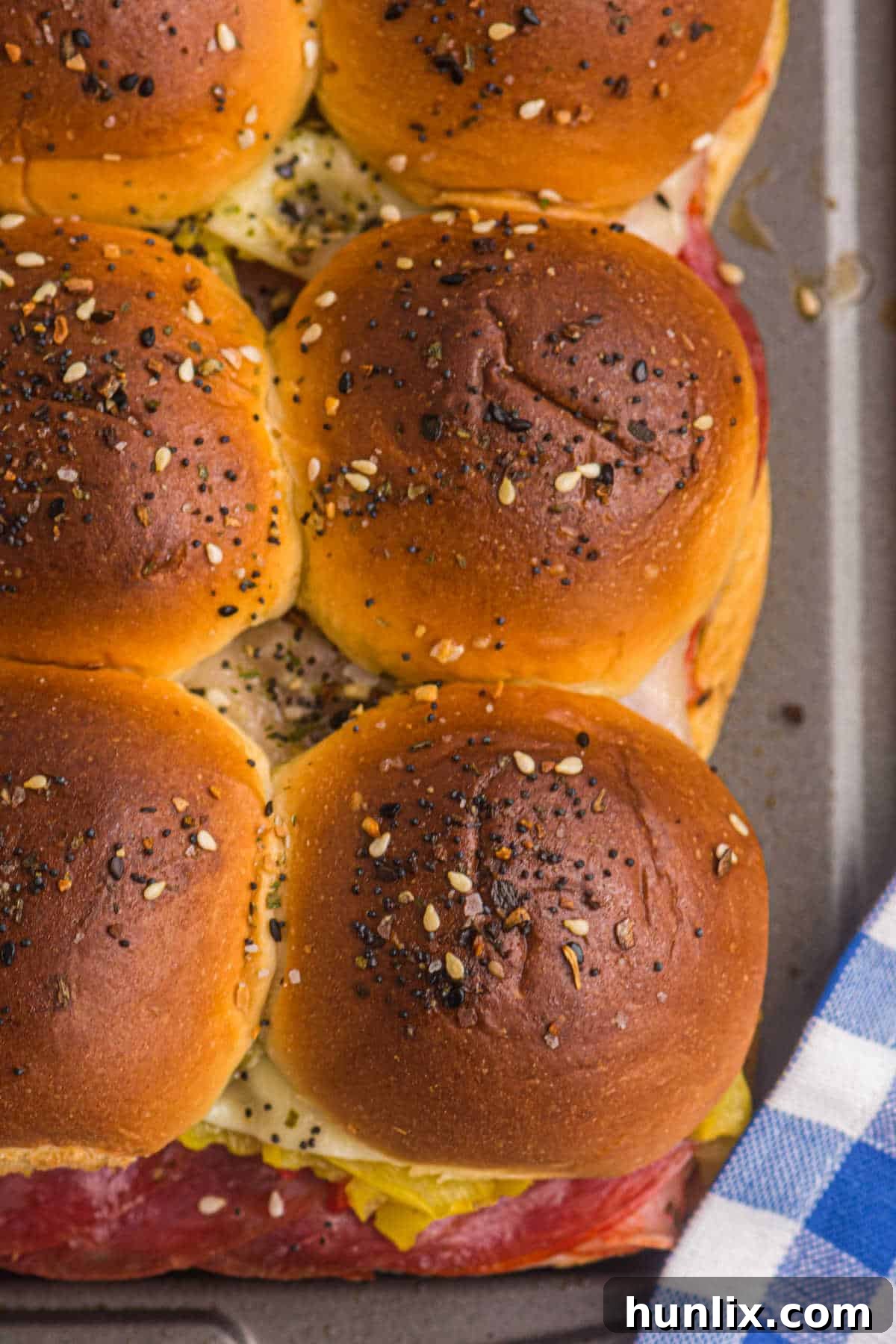 Another view of Italian sliders on a baking sheet, showcasing their golden-brown tops and melted cheese.
