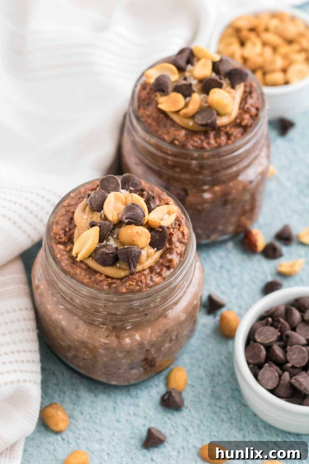 Dreamy Chocolate Peanut Butter Overnight Oats 2 Chocolate peanut butter overnight oats in mason jars, topped with chocolate chips and peanuts.
