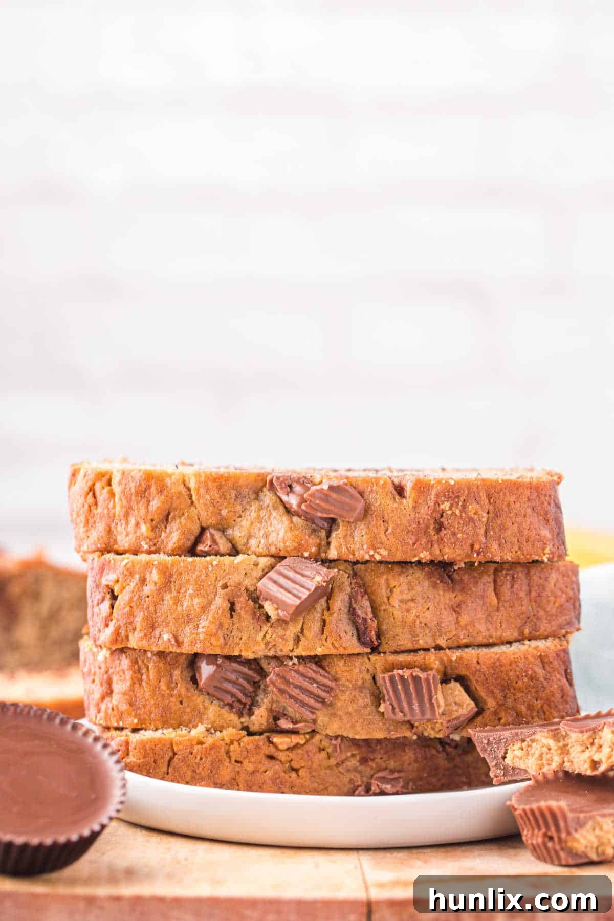 A stack of slices of Reese's peanut butter banana bread on a white plate, ready to be enjoyed.
