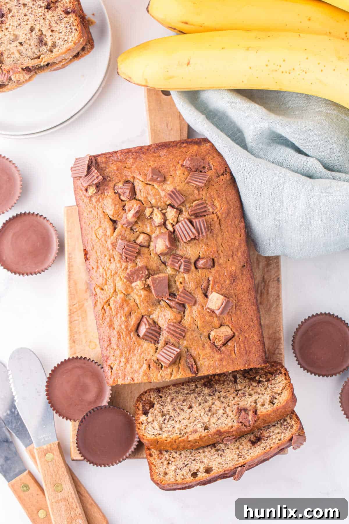 A beautiful loaf of Reese's peanut butter banana bread with two slices already cut, revealing the moist interior and chunks of peanut butter cups.