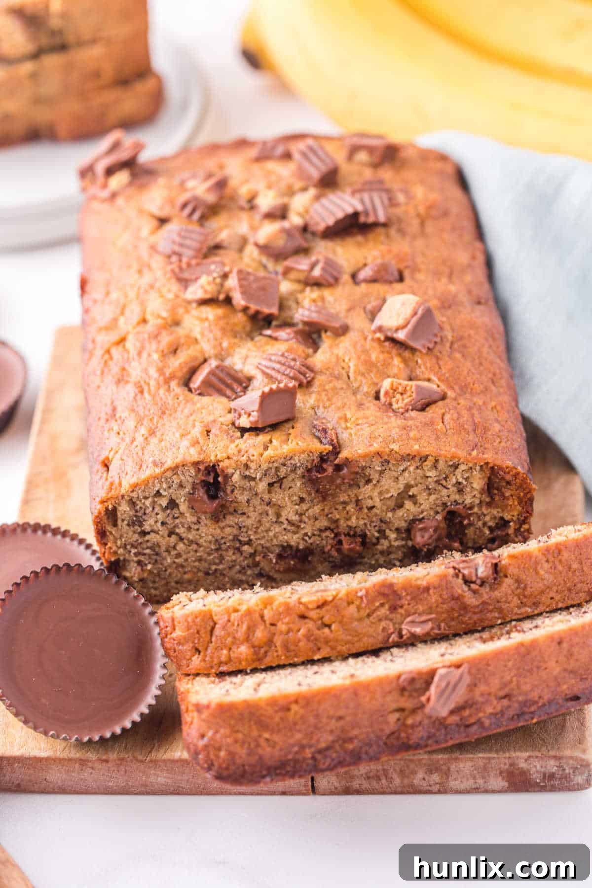 A whole loaf of Reese's peanut butter banana bread with a few slices cut off, revealing the moist interior and melted peanut butter cup pieces.