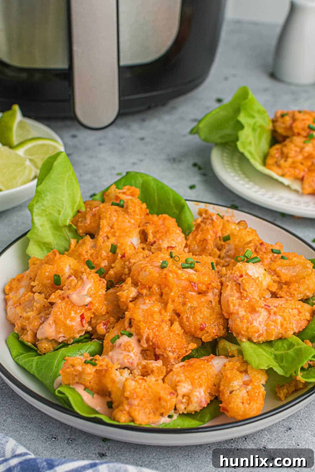 Crispy Air Fryer Bang Bang Shrimp 2 A plate of air-fried bang bang shrimp on a bed of fresh lettuce, garnished and ready to serve.