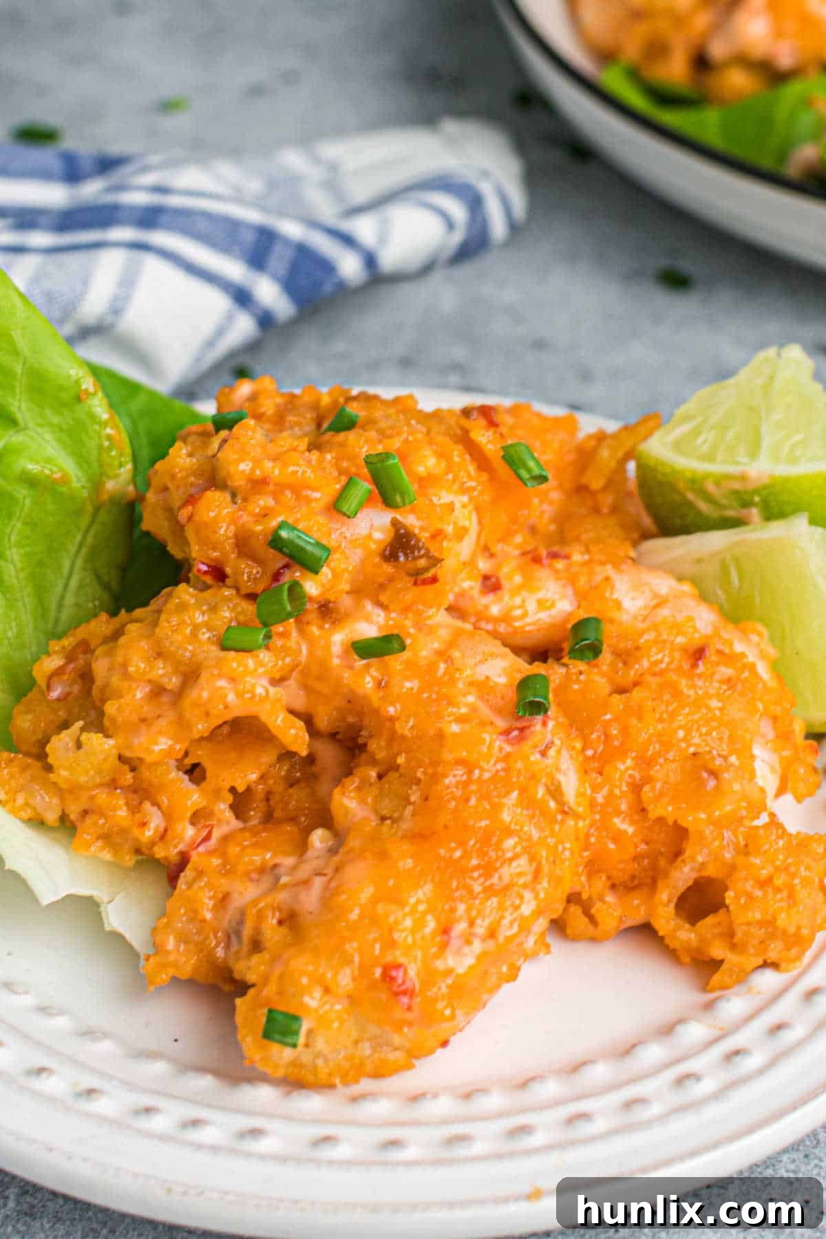 Crispy Air Fryer Bang Bang Shrimp 8 A plate of Air Fryer Bang Bang Shrimp garnished with lettuce and lime wedges, showcasing its vibrant presentation.