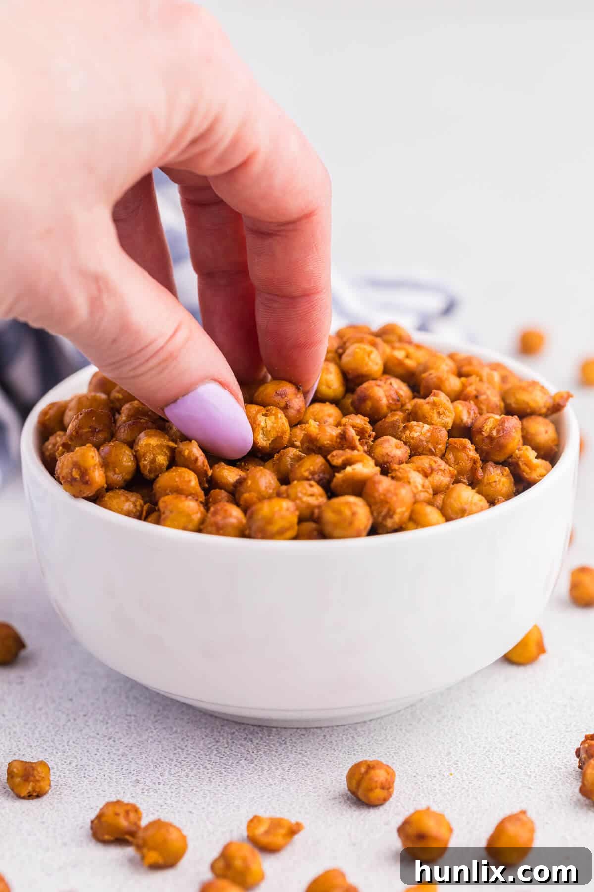A hand reaching in a bowl of taco roasted chickpeas.
