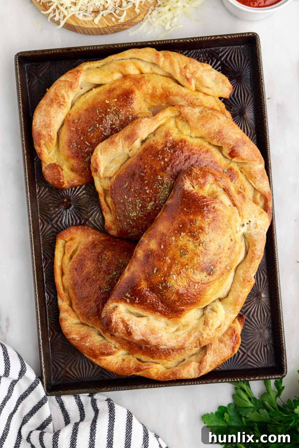 Freshly baked meat calzones on a baking sheet, golden brown and ready to serve.