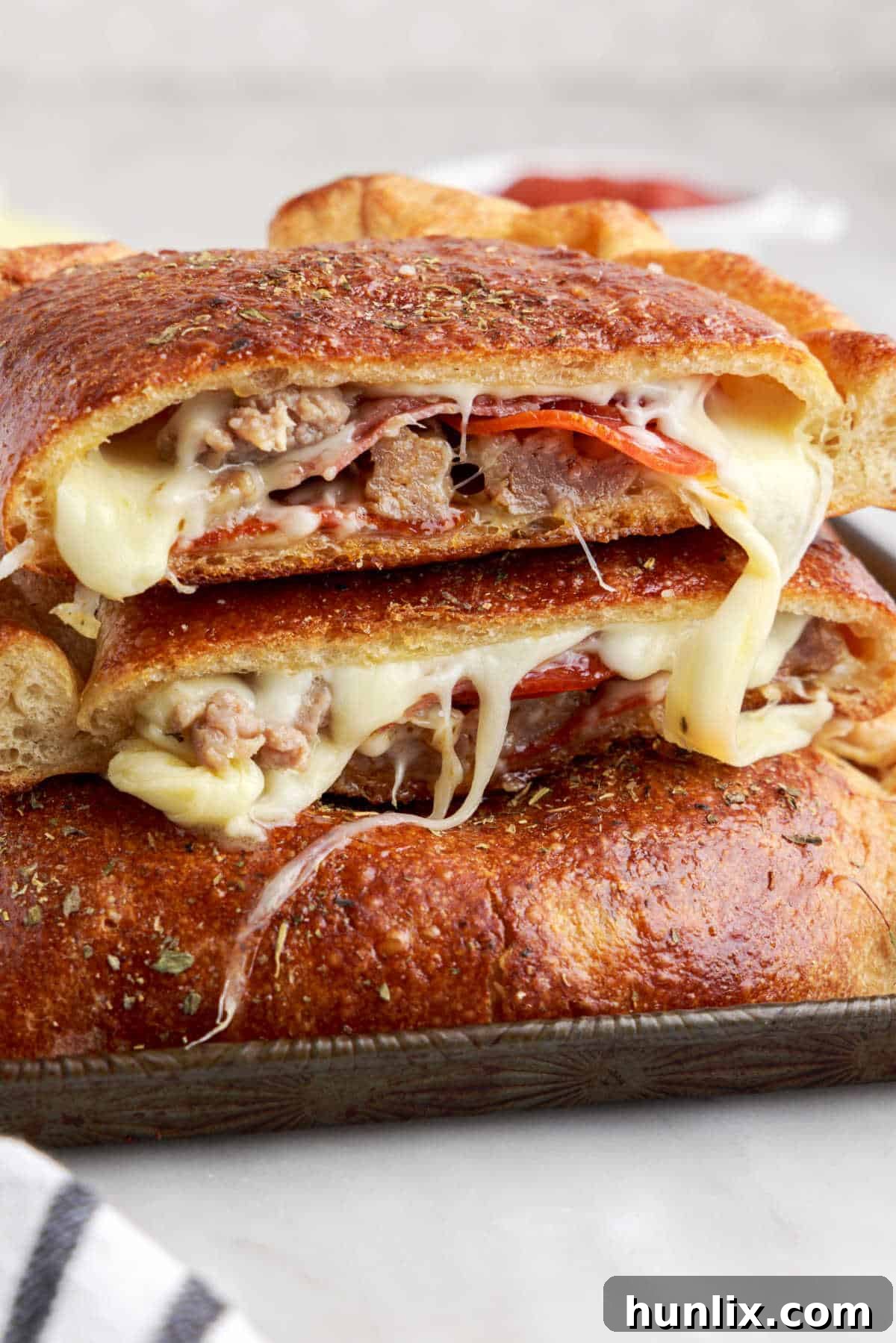 Sliced meat calzones, revealing the cheesy and meaty interior, stacked invitingly on a white surface.