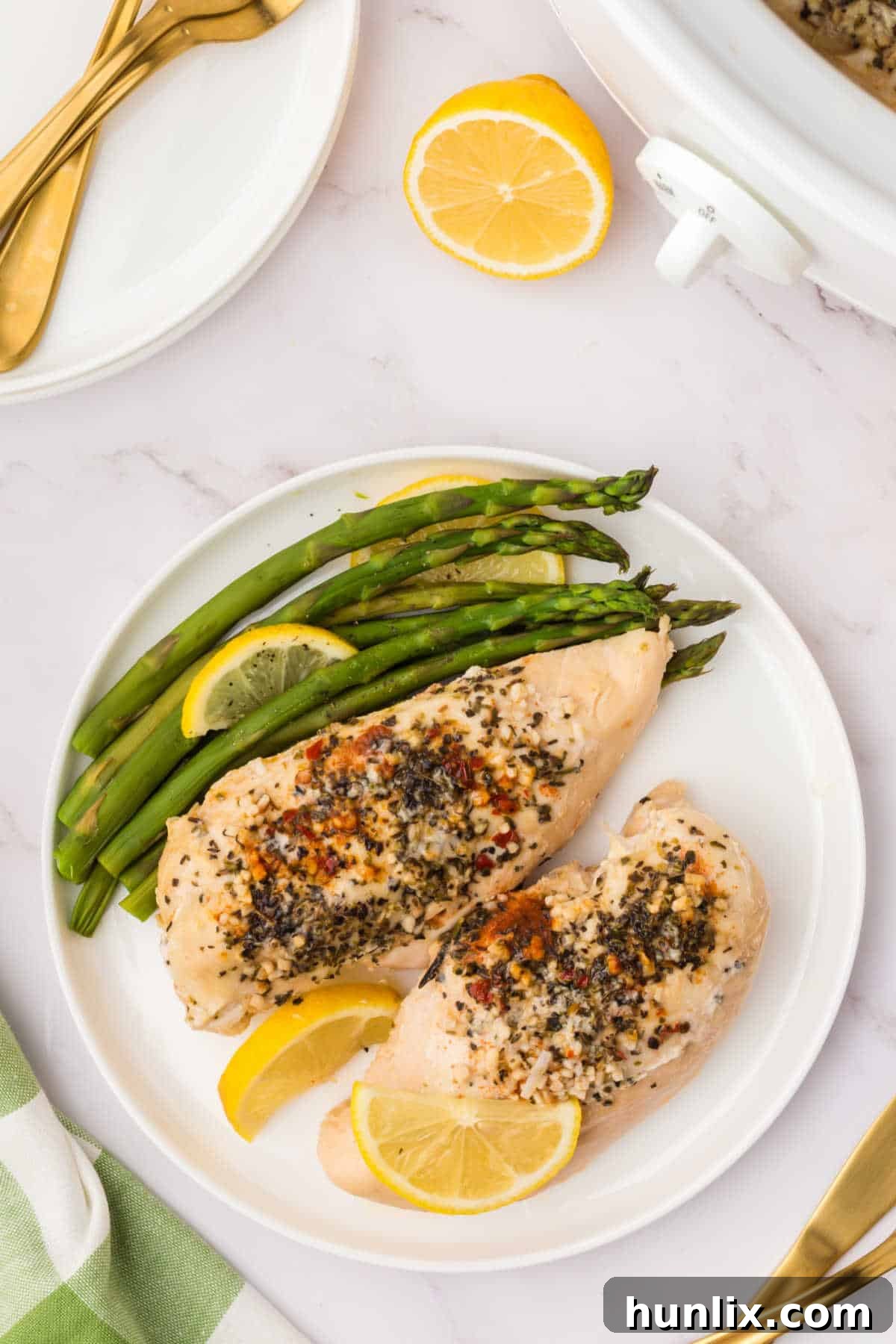 Crockpot Lemon Garlic Butter Chicken on a plate with asparagus and lemon slices.