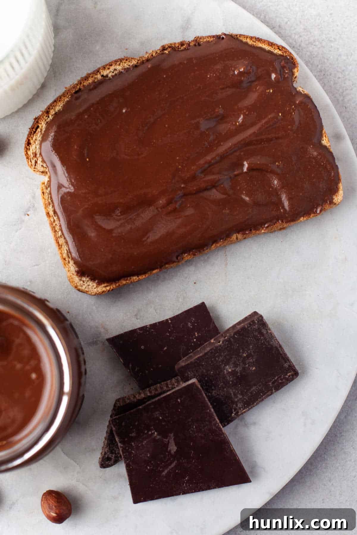 Decadent Homemade Chocolate Hazelnut Spread 8 A piece of golden brown toast generously spread with rich, creamy homemade Nutella, indicating a delicious breakfast or snack.