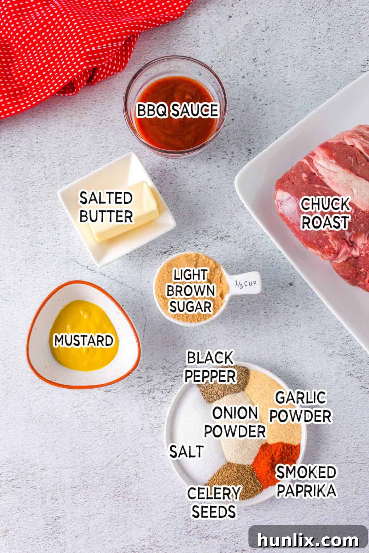 Assortment of dry rub spices, yellow mustard, and a chuck roast on a kitchen surface.