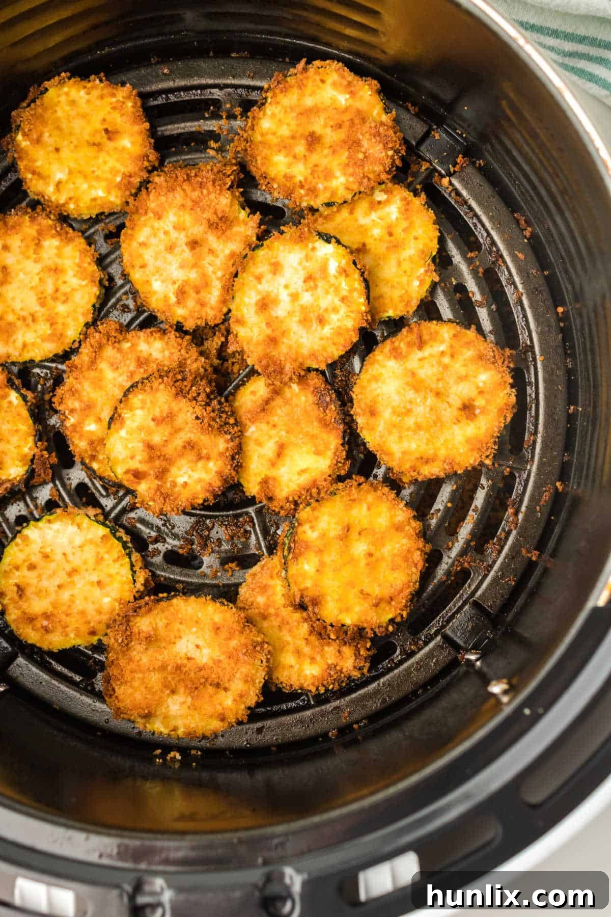 Golden Crispy Air Fryer Zucchini 2 Crispy Air Fryer Zucchini Chips in an air fryer basket, perfectly golden brown.