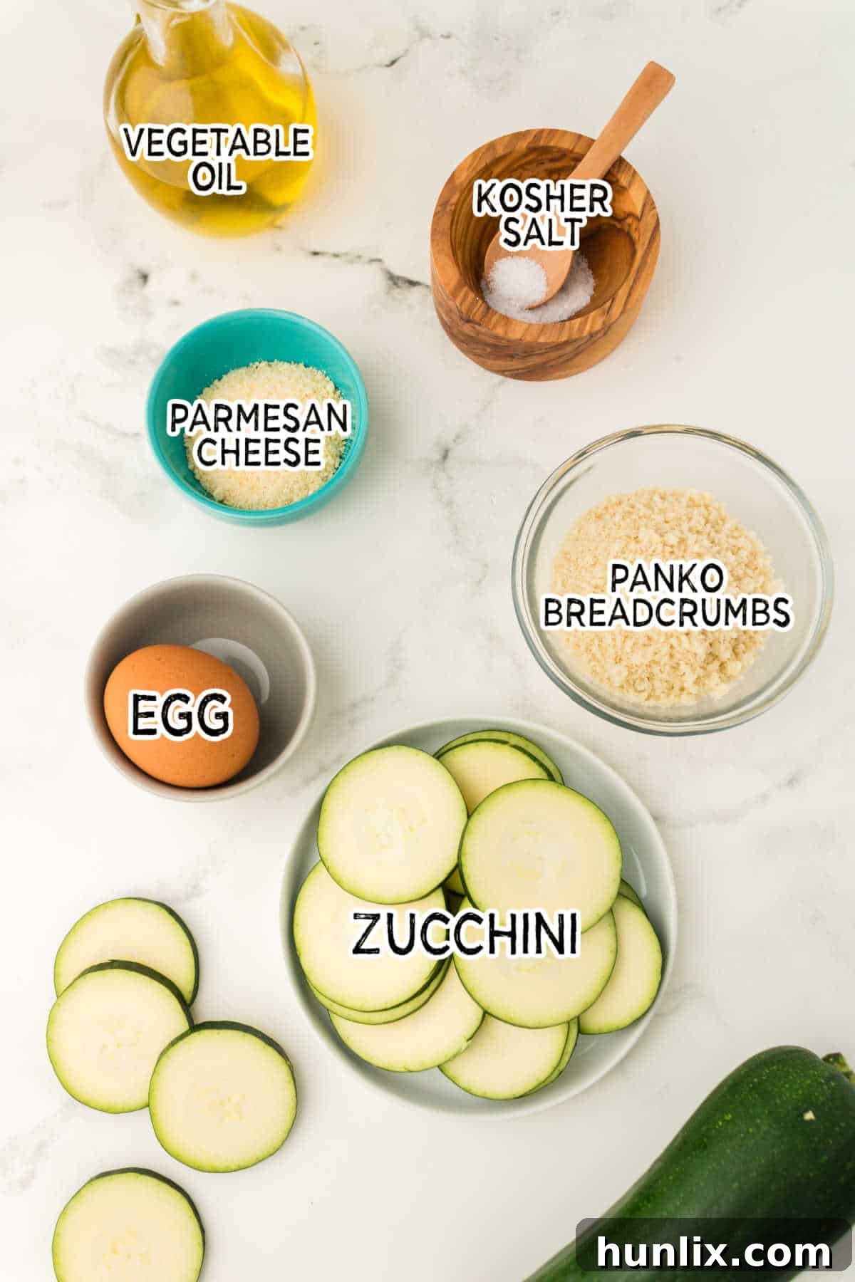 Golden Crispy Air Fryer Zucchini 3 Fresh ingredients laid out on a white marble counter for making air fryer zucchini chips.