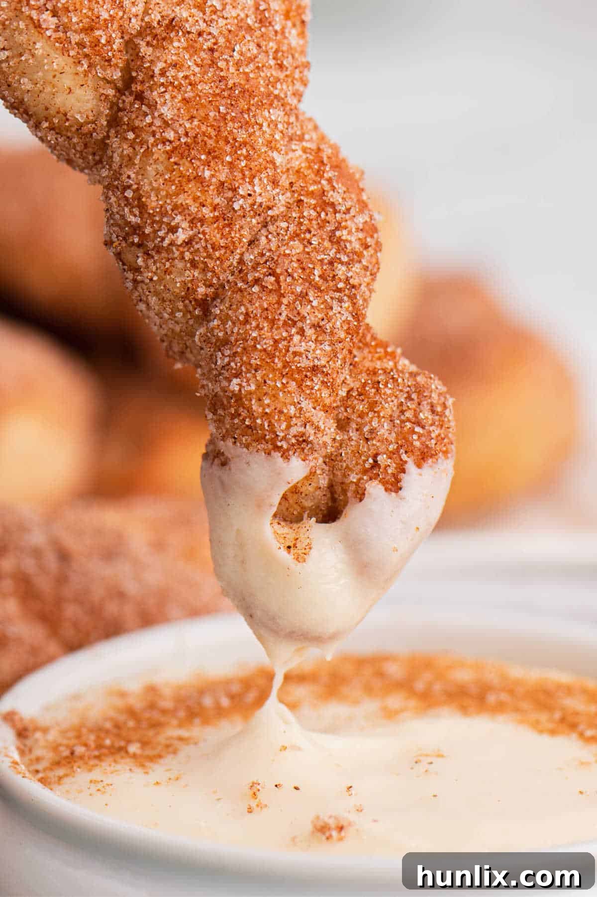 Air fryer cinnamon twists dipped in cream cheese sauce, highlighting the delicious combination.