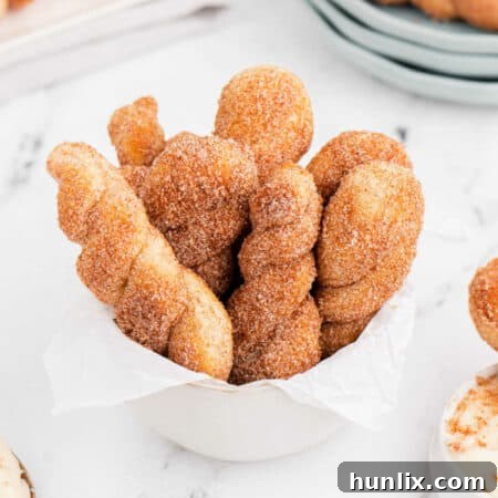 Air fryer cinnamon twists with cream cheese dip in a white dish.