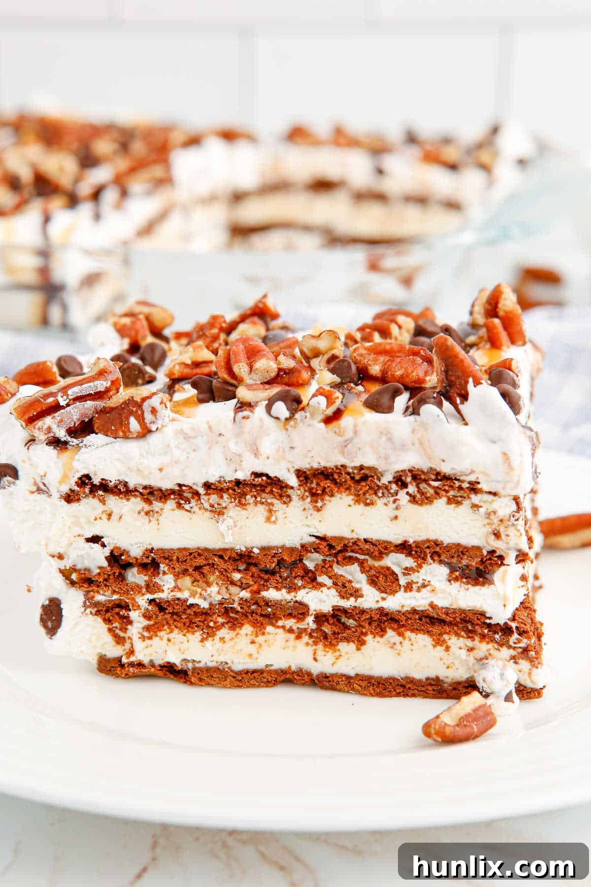 A beautifully cut slice of Turtle Ice Cream Sandwich Cake on a white plate, ready to be enjoyed.