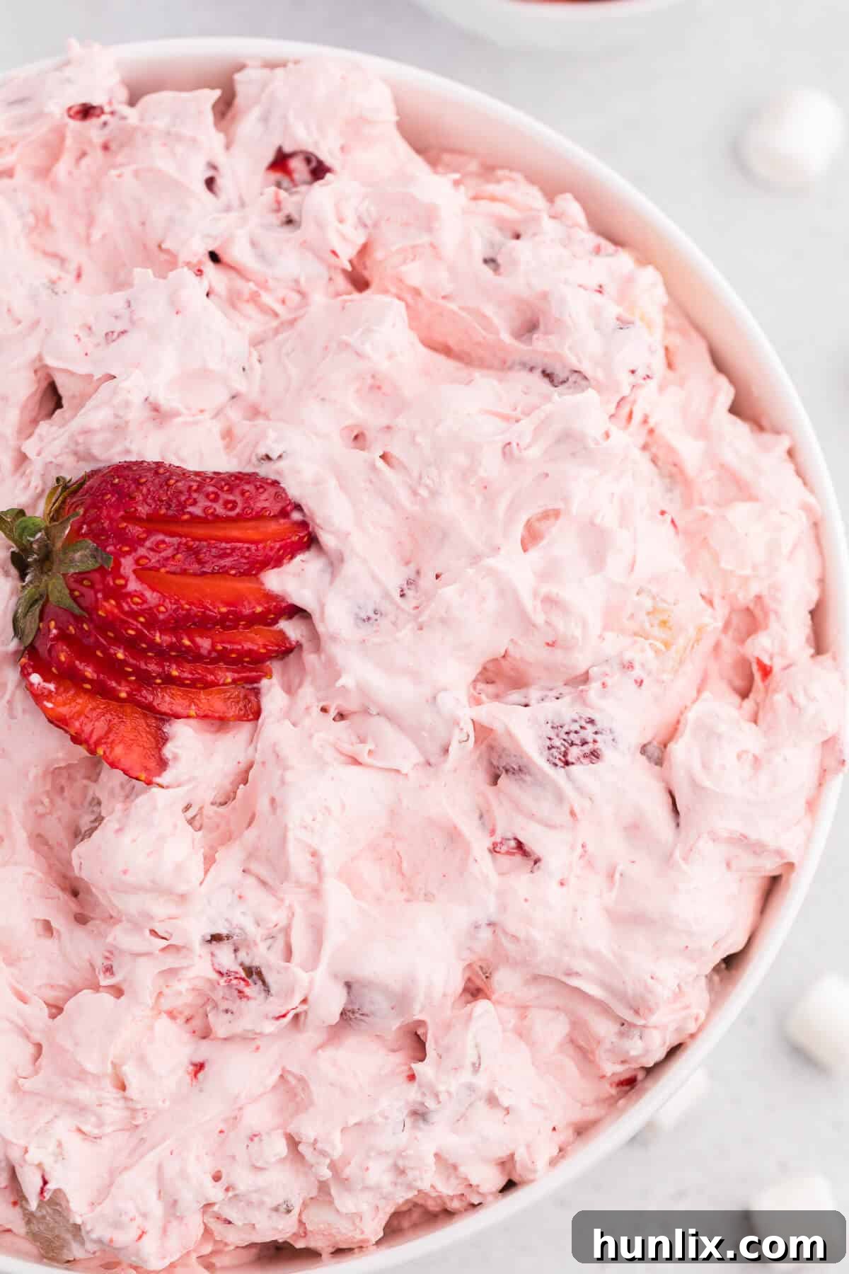Strawberry fluff salad in a elegant white serving bowl, ready for enjoyment.