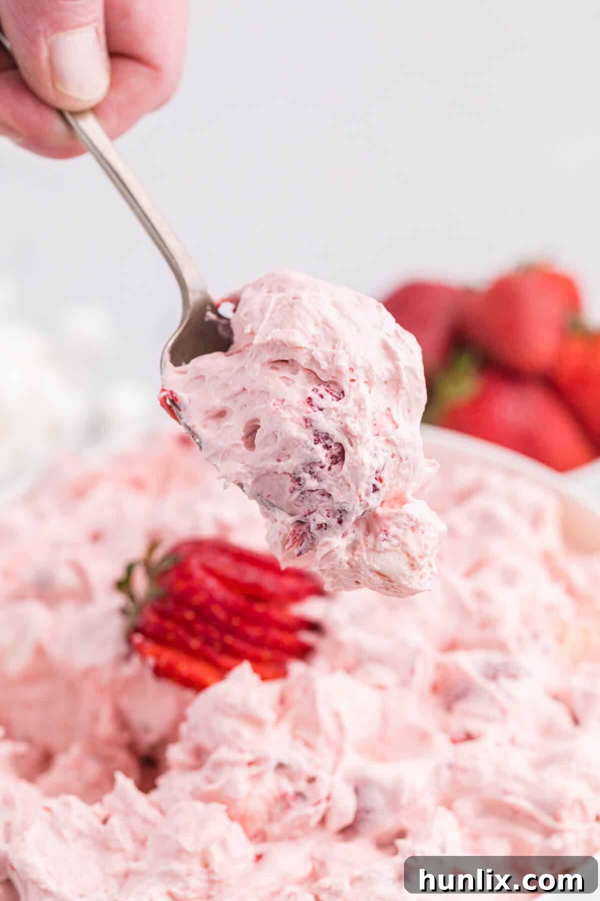 A spoonful of strawberry fluff salad, showcasing its pink, fluffy texture.