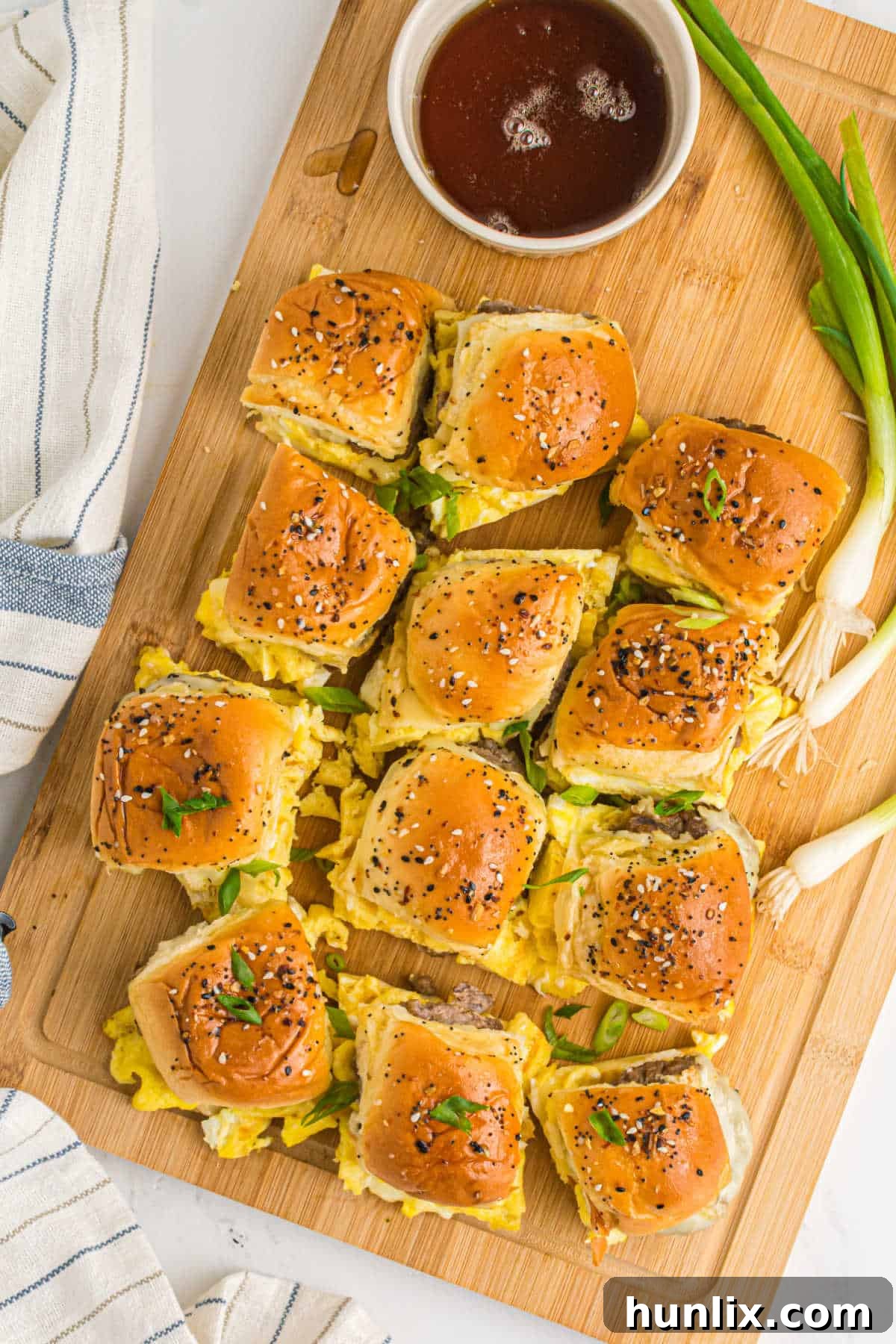Buttery breakfast sliders with sausage, egg, and cheese on a wooden cutting board, ready to serve at brunch.