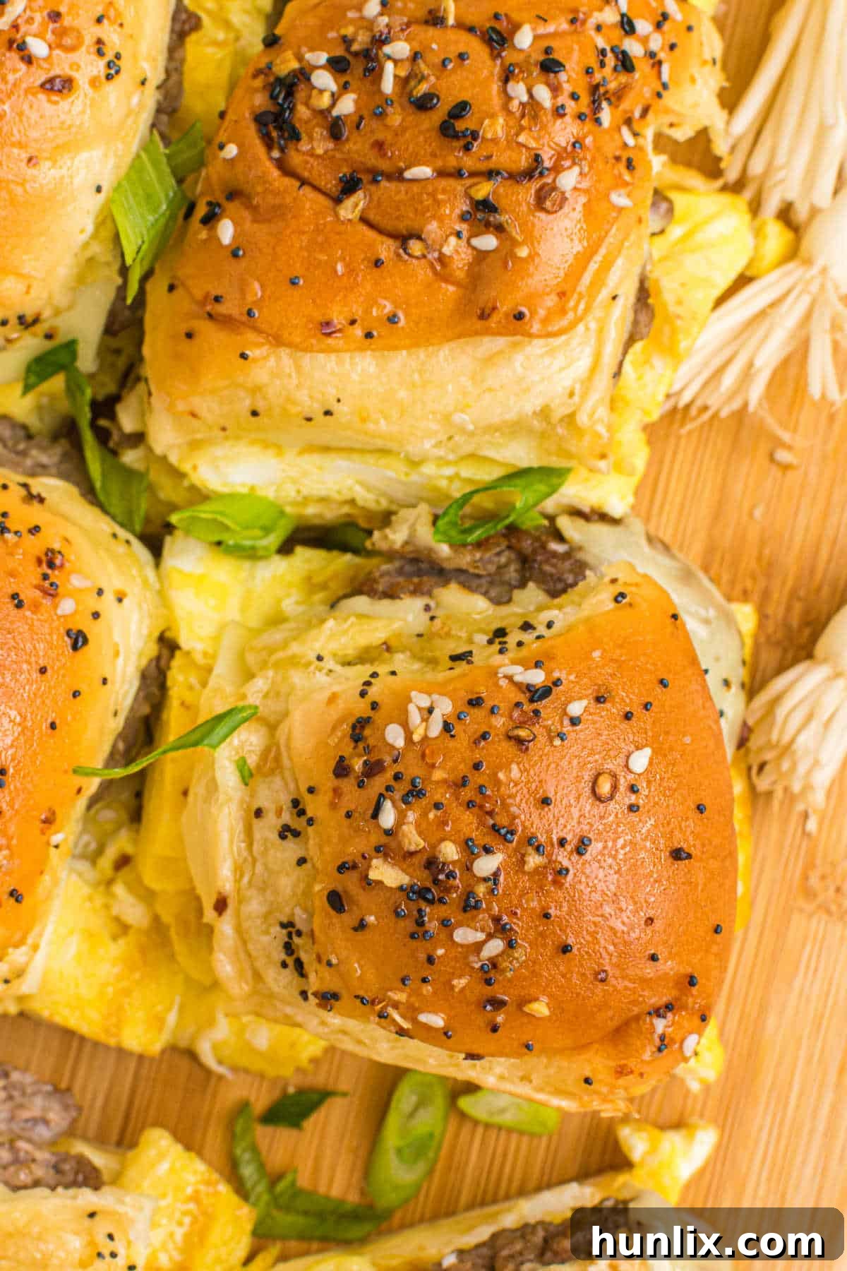 A serving of golden-brown breakfast sliders on a wooden cutting board, garnished lightly, ready for a gathering.