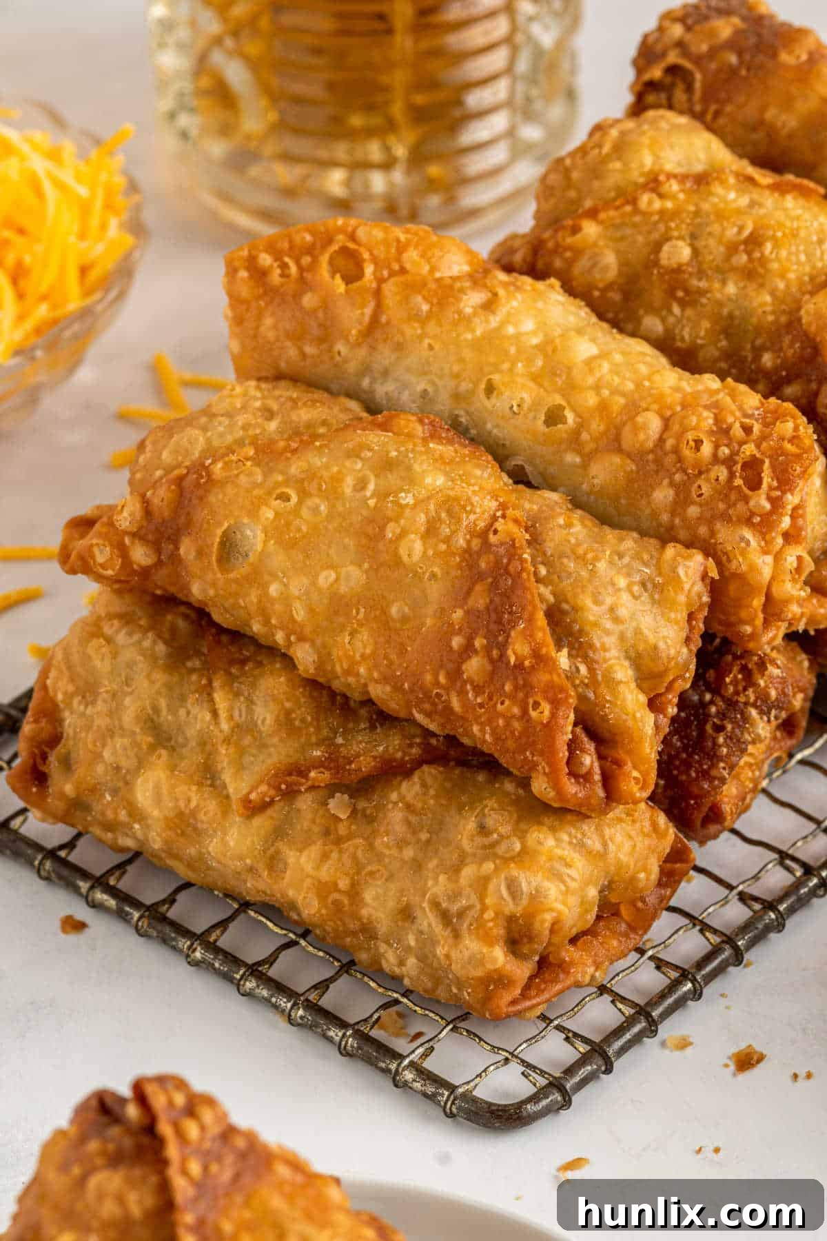Crispy Cheeseburger Bundles 7 Cheeseburger egg rolls stacked on a wire rack.