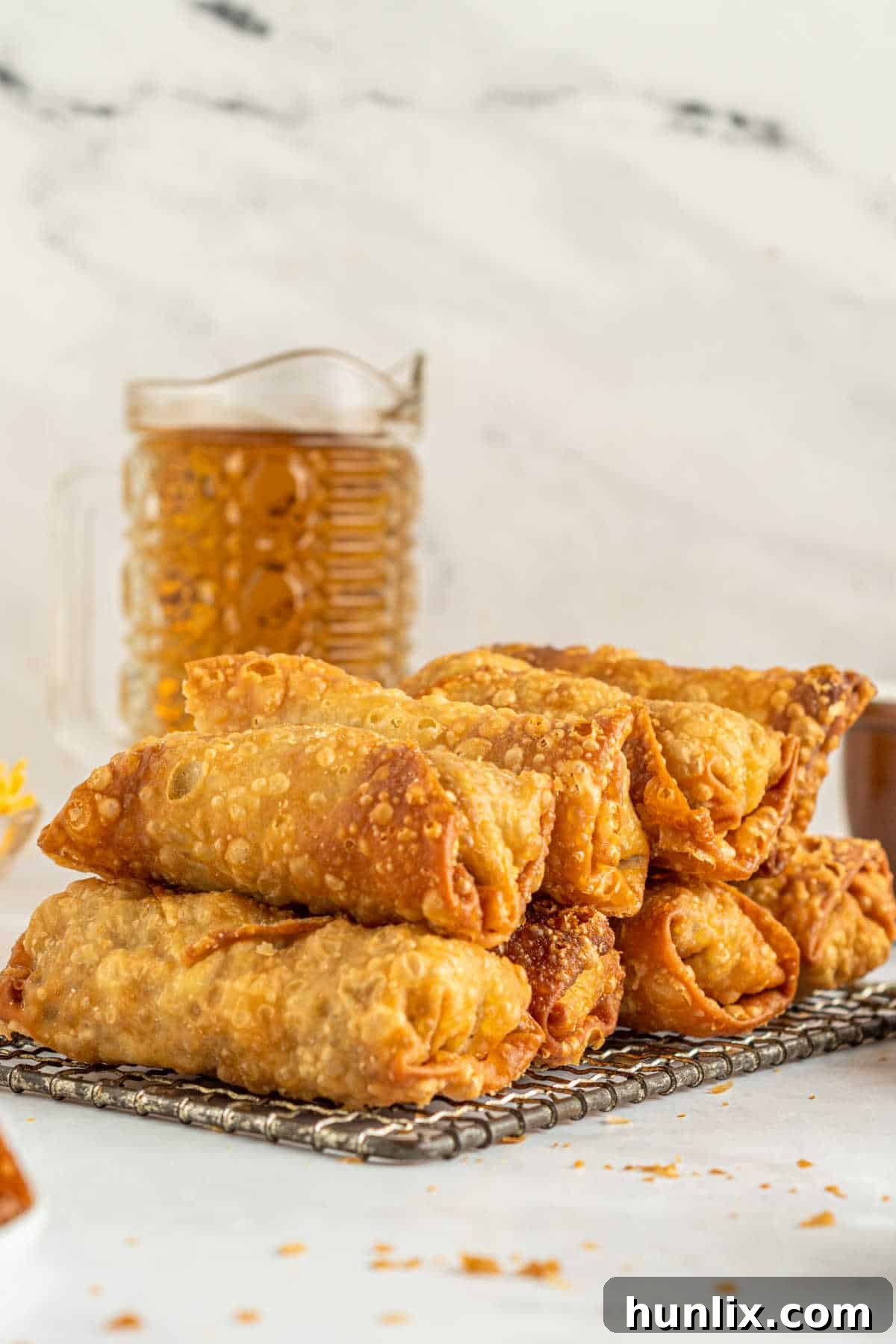 Crispy Cheeseburger Bundles 8 Cheeseburger egg rolls stacked on a wire rack.