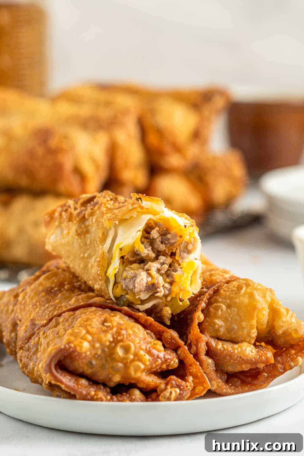 Crispy Cheeseburger Bundles 9 Cheeseburger egg rolls on a plate with a bite out of the top egg roll.