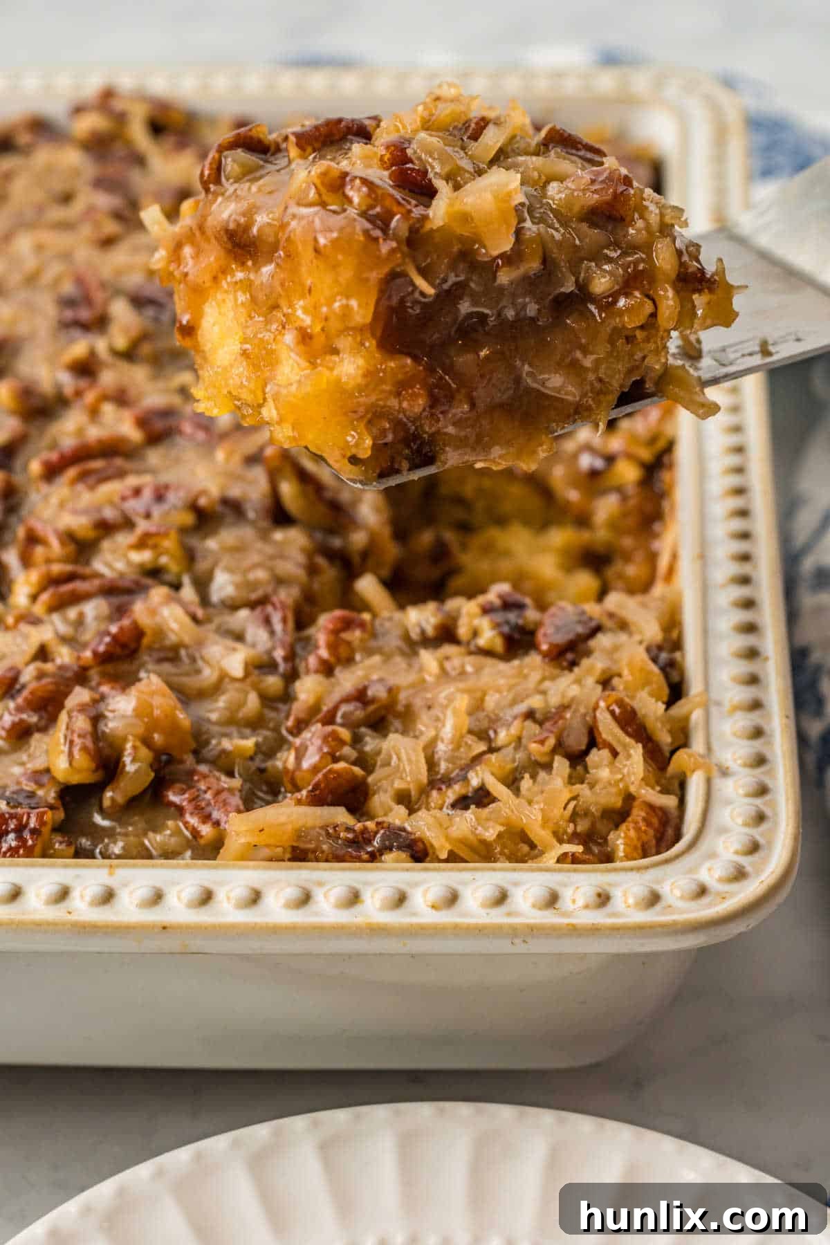A delectable piece of Tornado Cake served on a spatula, showcasing its moist texture and rich topping.