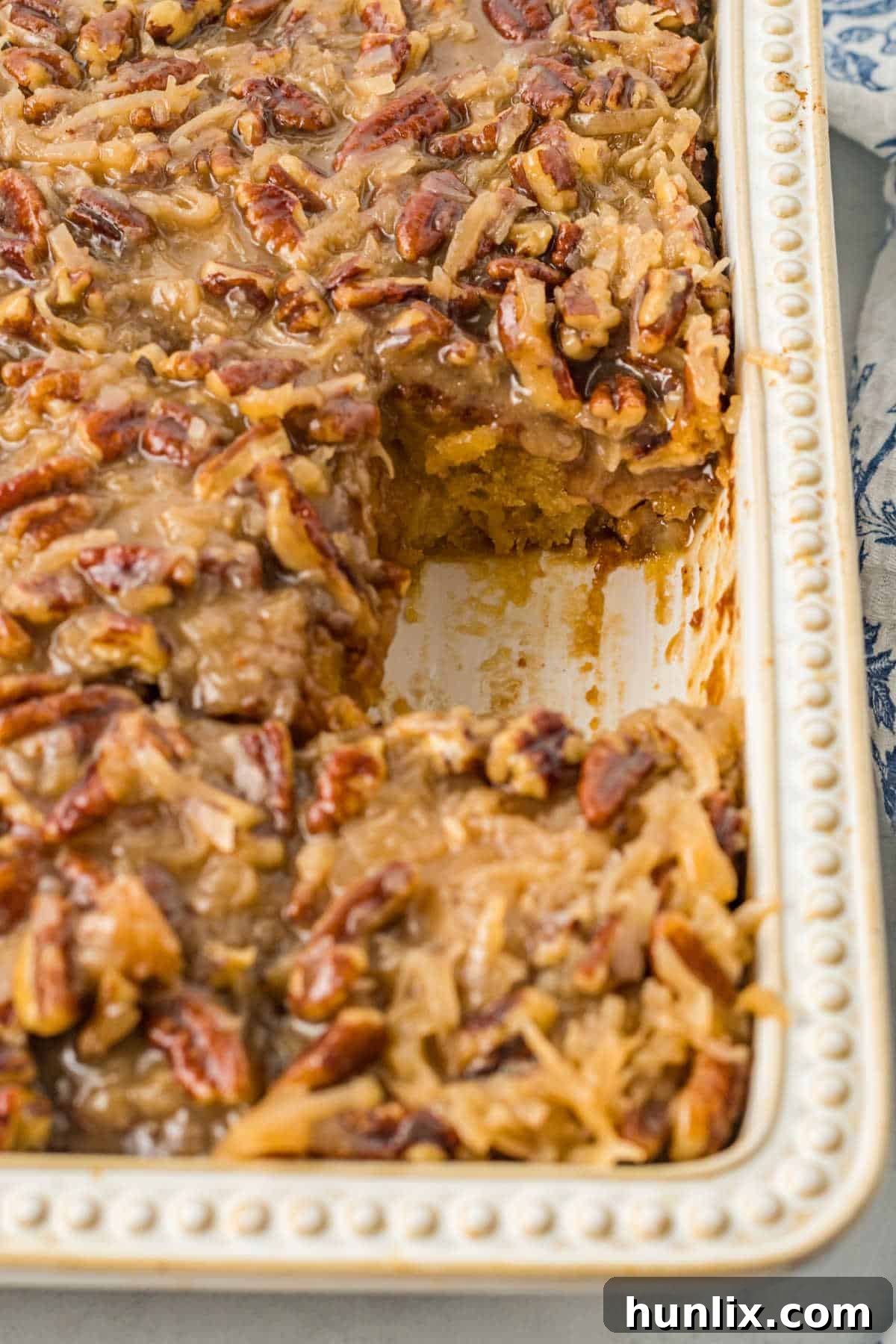 A pan of Tornado Cake with a slice already removed, highlighting its rich, gooey topping.