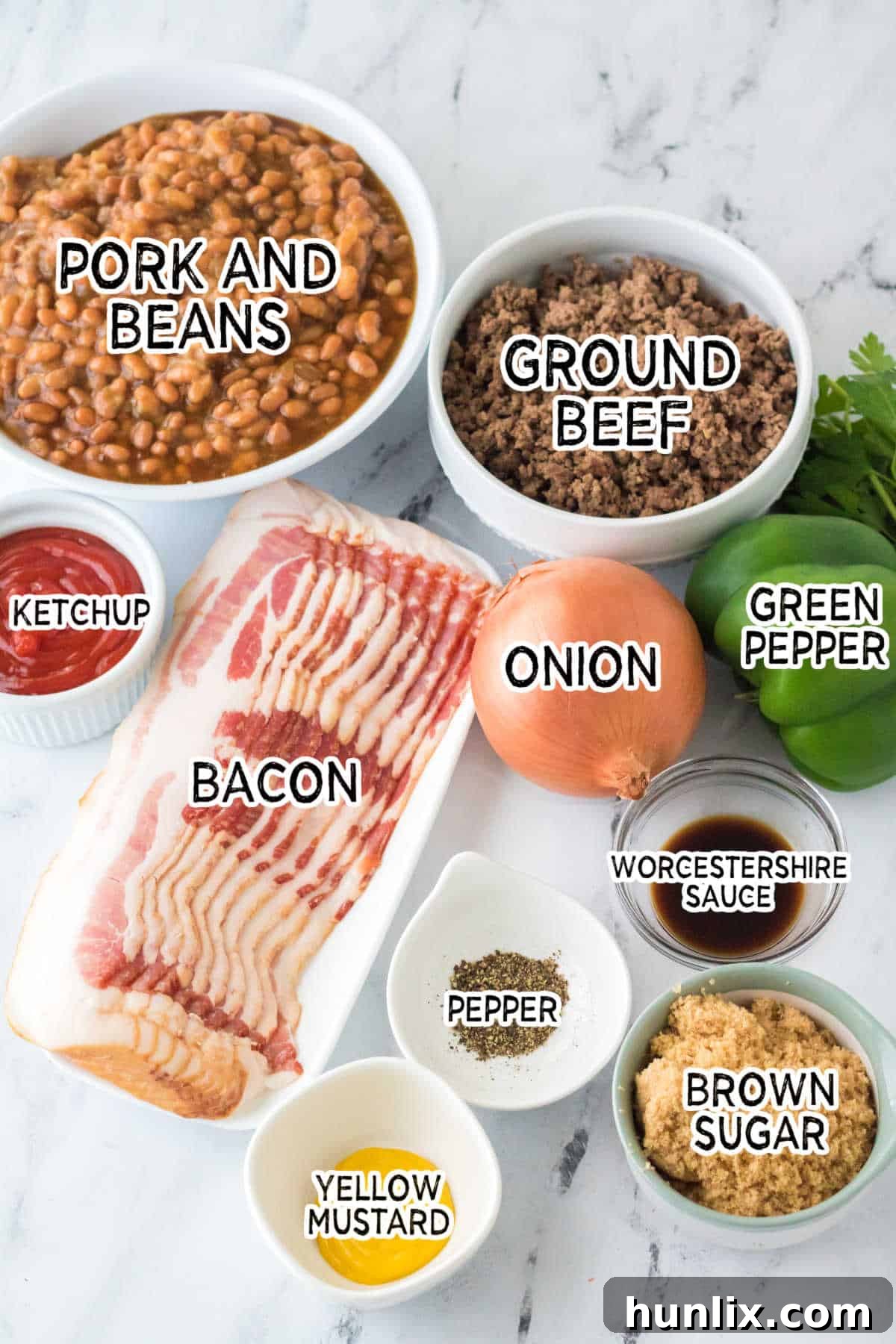 Assortment of fresh ingredients laid out, including canned beans, ground beef, bell pepper, onion, brown sugar, ketchup, and bacon, ready for preparation.