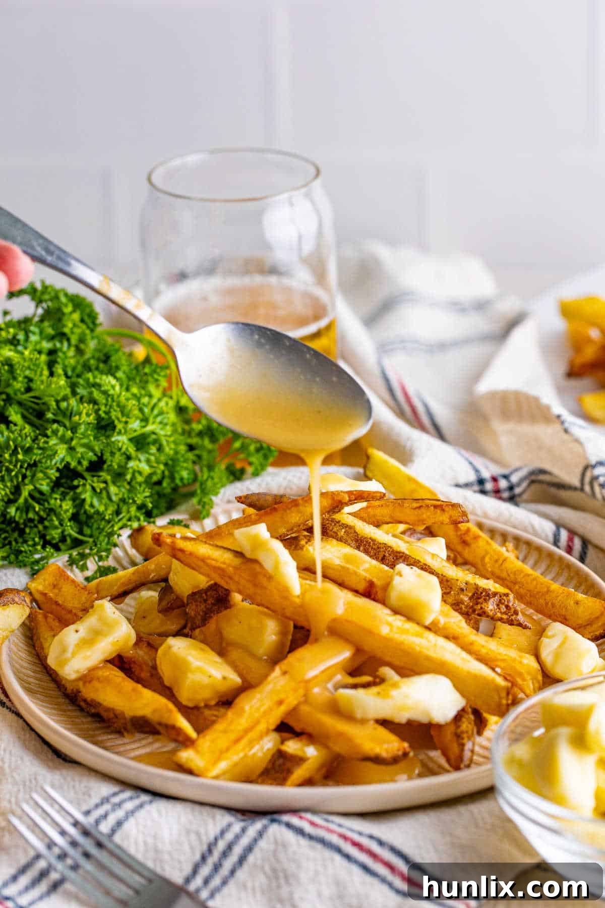 Canada's Iconic Comfort Food 2 A spoon drizzling gravy on a fresh plate of poutine, highlighting the crispy fries and melting cheese curds.