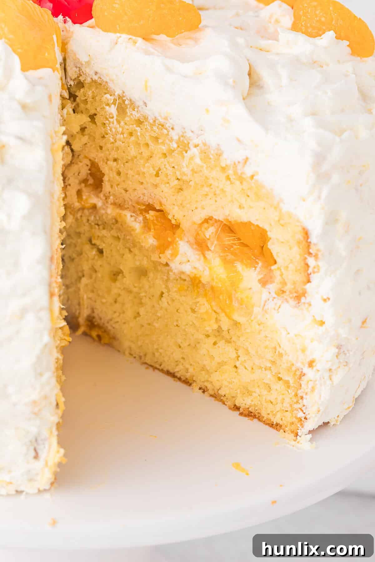 Sunshine Citrus Cloud Cake 8 A perfectly sliced Pig Pickin' Cake on a white serving plate, showing its distinct layers of moist cake and creamy pineapple frosting, ready to be enjoyed.