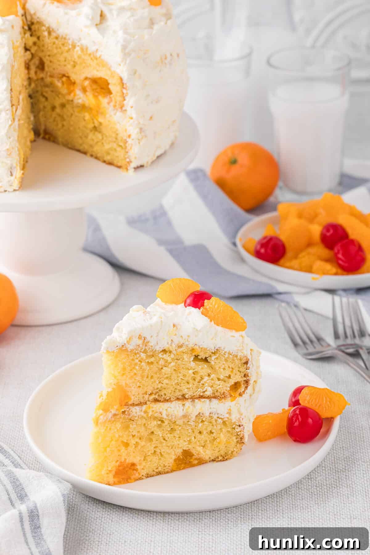 Sunshine Citrus Cloud Cake 9 A single slice of Pig Pickin' Cake artfully placed on a white plate, showcasing the delicate cake layers, the rich pineapple frosting, and mandarin orange segments.