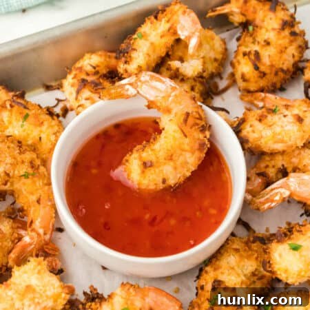 A shrimp in dipping sauce on a baking sheet with more of the recipe.