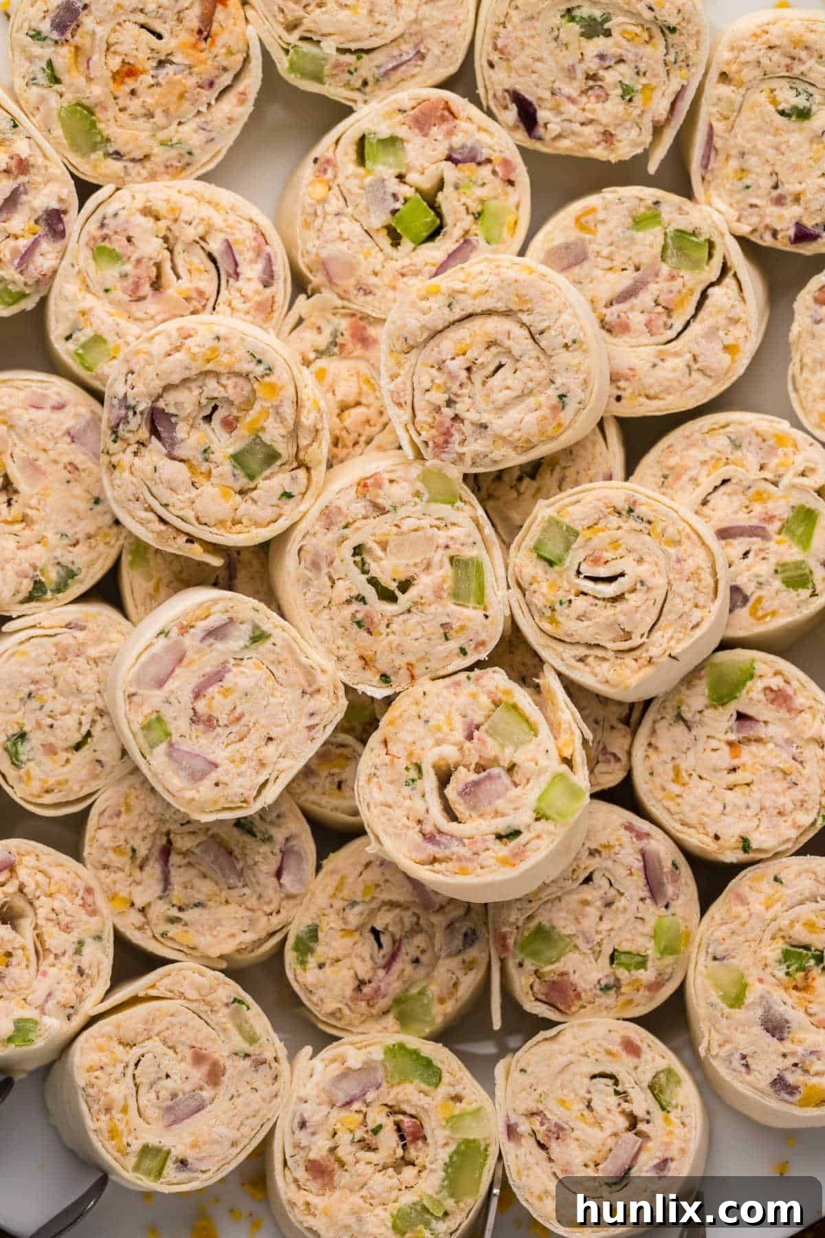 A tightly arranged group of chicken pinwheels on a white plate, ready for serving.