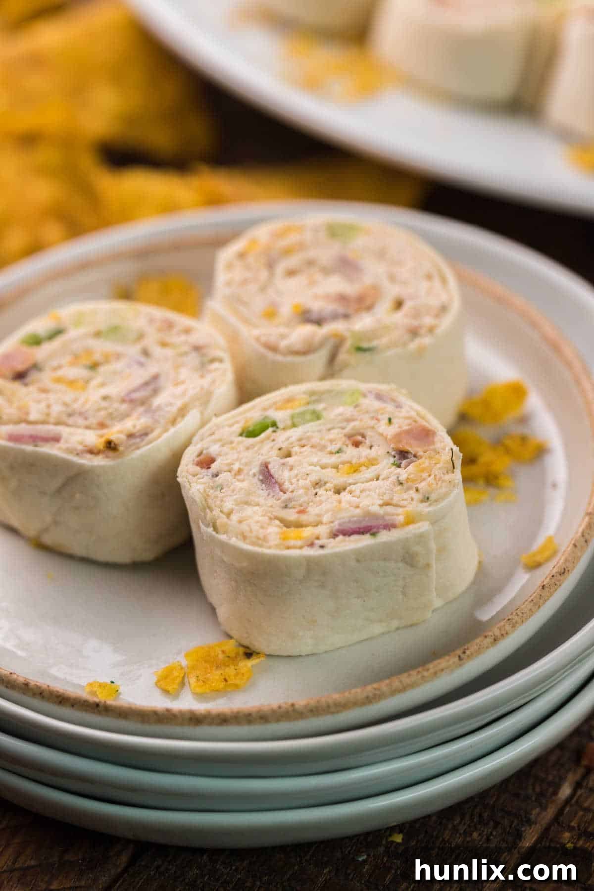 Three perfectly cut chicken pinwheels neatly arranged on a small white plate.