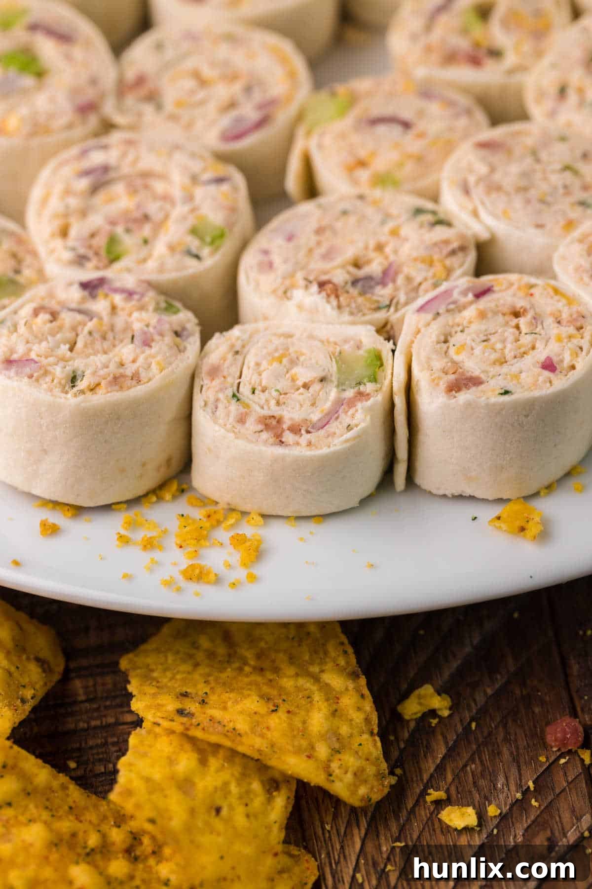 A festive platter of chicken pinwheels adorned with fresh green herbs, ready to be served at a party.