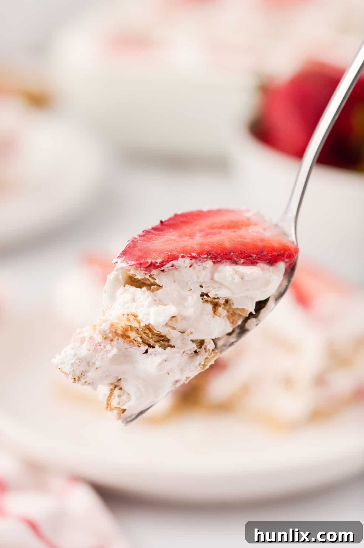 A fork holding a bite-sized piece of strawberry icebox cake, ready to be enjoyed.