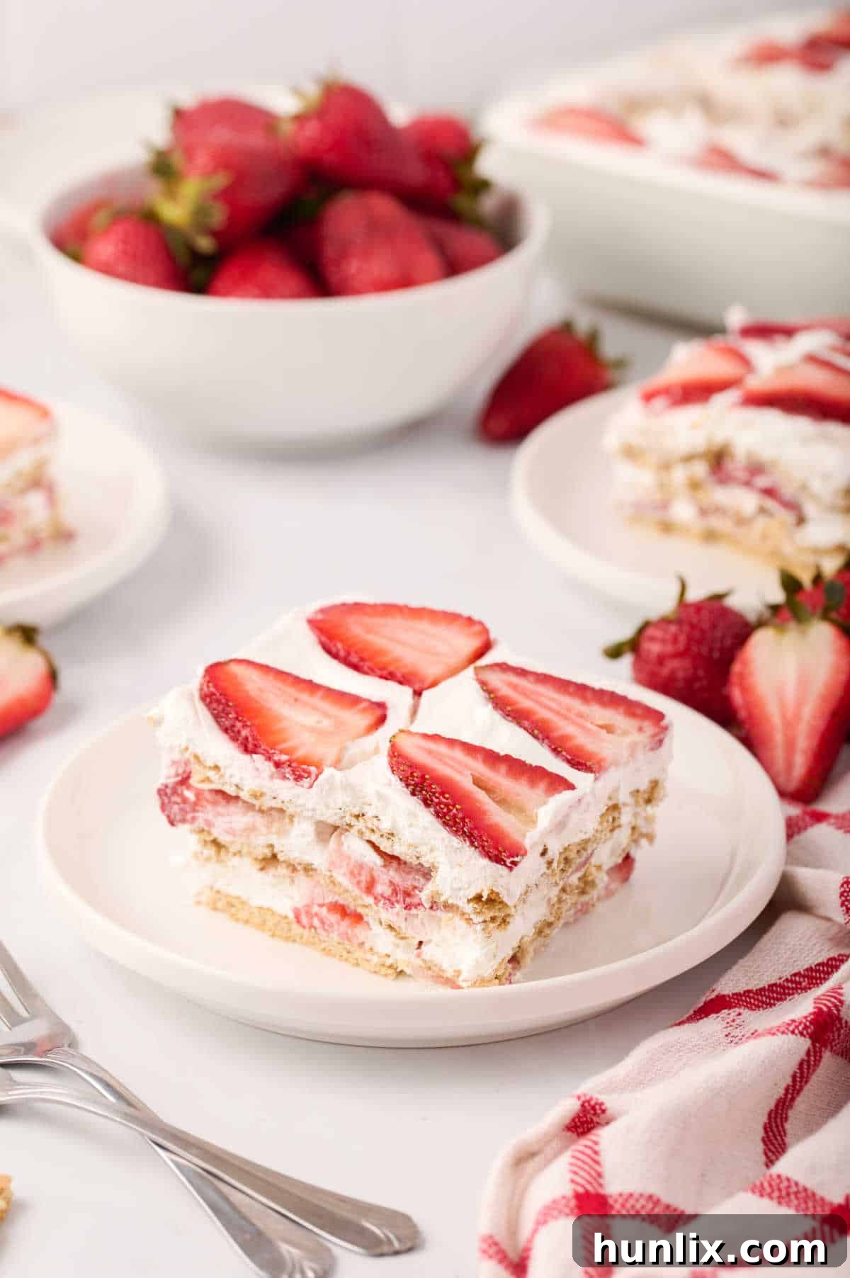 A beautifully presented slice of strawberry icebox cake on a white plate, showcasing its distinct layers.