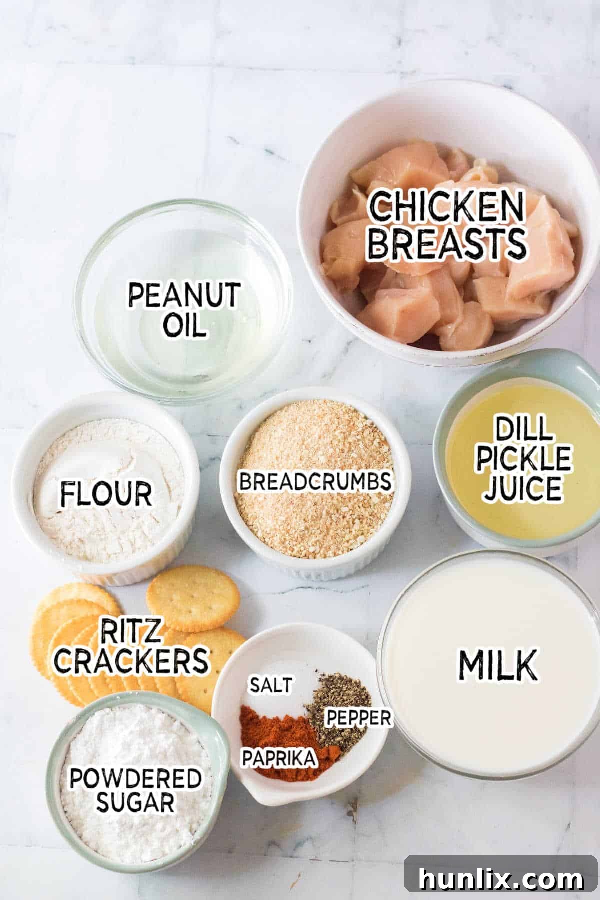 The Ultimate Homemade Chick-fil-A Nuggets 3 A flat lay image displaying all the raw ingredients needed to prepare the copycat Chick-fil-A chicken nuggets, including chicken, milk, pickle juice, crackers, breadcrumbs, flour, and spices.