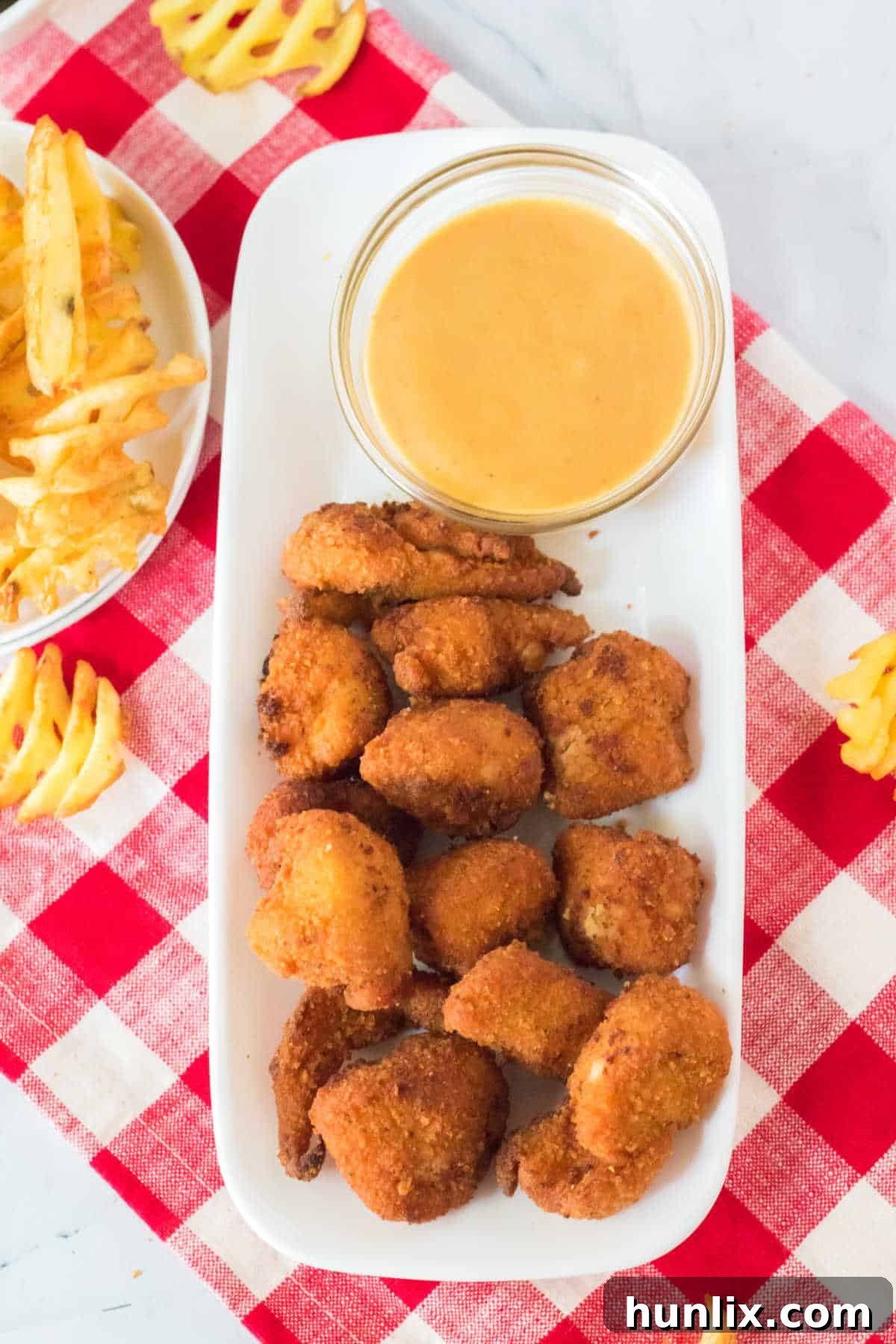The Ultimate Homemade Chick-fil-A Nuggets 7 A platter brimming with crispy copycat Chick-fil-A nuggets and a bowl of the homemade dipping sauce, presented alongside golden waffle fries.