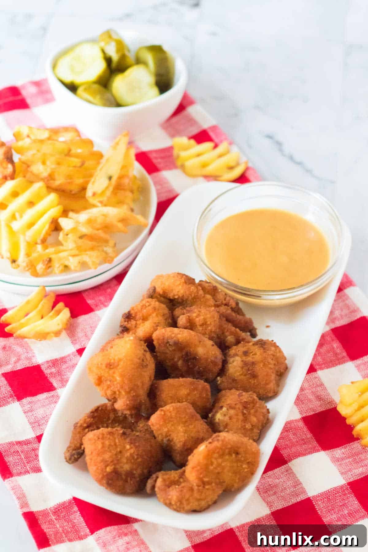 The Ultimate Homemade Chick-fil-A Nuggets 8 A close-up shot of crispy homemade Chick-fil-A nuggets and a bowl of dipping sauce on a platter, showcasing their golden texture.